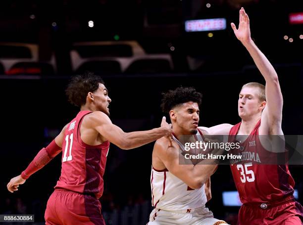 Bennie Boatwright of the USC Trojans drives between Trae Young and Brady Manek of the Oklahoma Sooners during the Basketball Hall of Fame Classic at...