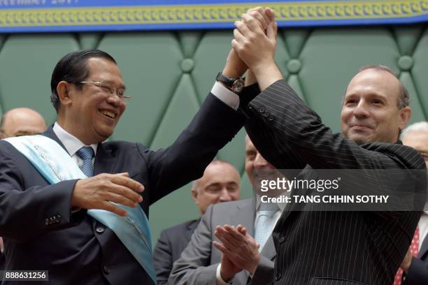 European Council on Tourism and Trade president Anton Caragea and Cambodian Prime Minister Hun Sen raise their hands during a handover ceremony of...