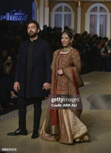 Pakistani Actor Shan and actress Uzma Hassan present a creation by Pakistani fashion designer Fahad Hussayn during the Pantene Hum Bridal Couture...