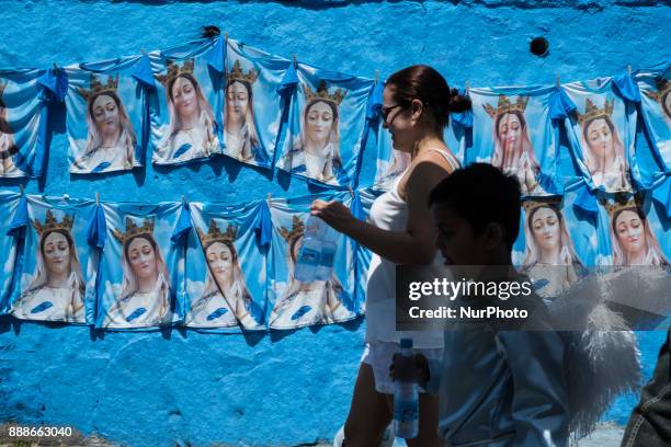 Child dressed as an angel is seen passing through a wall full of shirts of the Immaculate Conception, during the feast in homage to the Catholic...