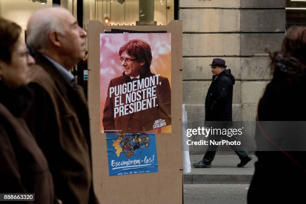 People walk past an election campaign poster of the candidate of the Junts Per Catalunya party and Catalonia's deposed regional president Carles...