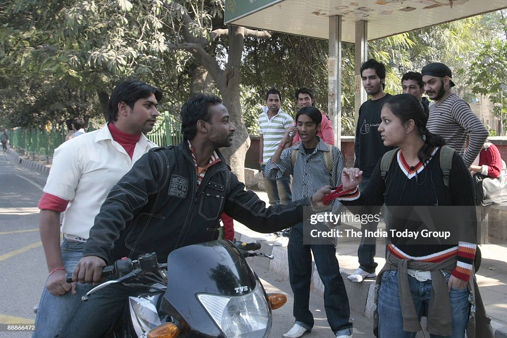 Jamghat Volunteers stage an invisible theatre skit on sexual harassment in Delhi, India ( Members of Jamghat staging an Invisible theatre performing, There is a motley group of people at a bus stop. Two boys on a motorbike pull up and start needling a cou
