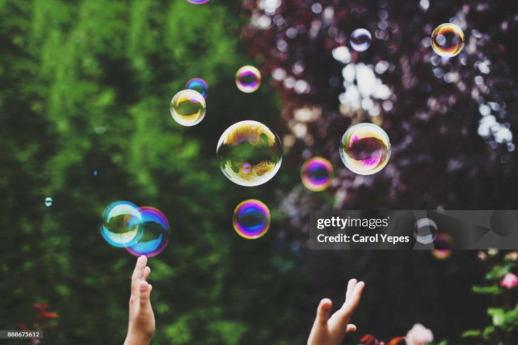 Hands trying to catch soap bubbles
