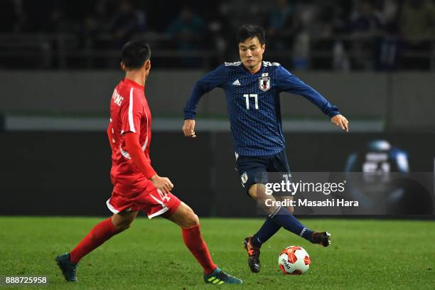 Yasuyuki Konno of Japan takes on Pak Myong Song of North Korea during the EAFF E-1 Men's Football Championship between Japan and North Korea at...