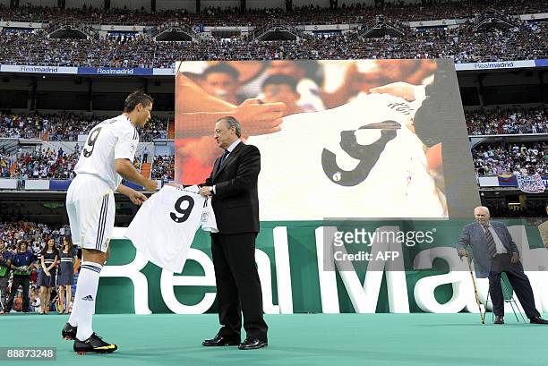Real Madrid's new player Portuguese Cristiano Ronaldo gives his signed new number 9 jersey next to Real Madrid president Florentino Perez next to...