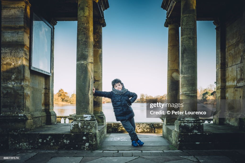 Young boy leaning against a pillar.