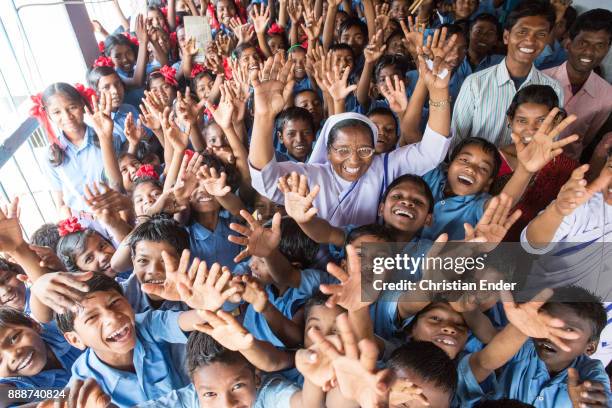 Jibanpur, India Group portrait of school kids with nuns and teachers holding up their hands towards the camera, at a elementary school in Jibanpur.