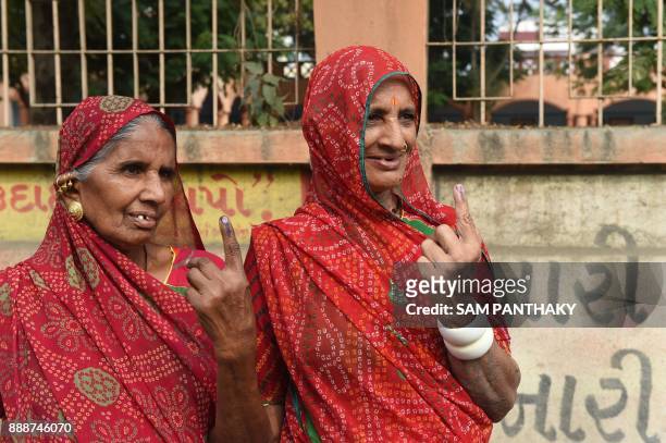 Indian voters show their inked fingers after casting their ballots during the first phase of Vidhan Sabha elections of Gujarat state in Limbdi, some...