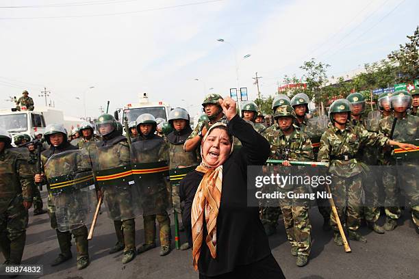 An Uighur woman protests in front of policemen at a street on July 7, 2009 in Urumqi, the capital of Xinjiang Uighur autonomous region, China....