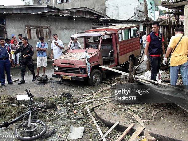 Investigators look for evidence after a bomb blast at a commercial center in Jolo, on the island of Mindanao on July 7, 2009. At least six people...