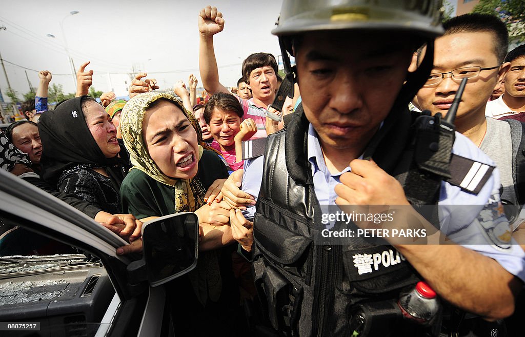 Ethnic Uygur women grab a riot policemen
