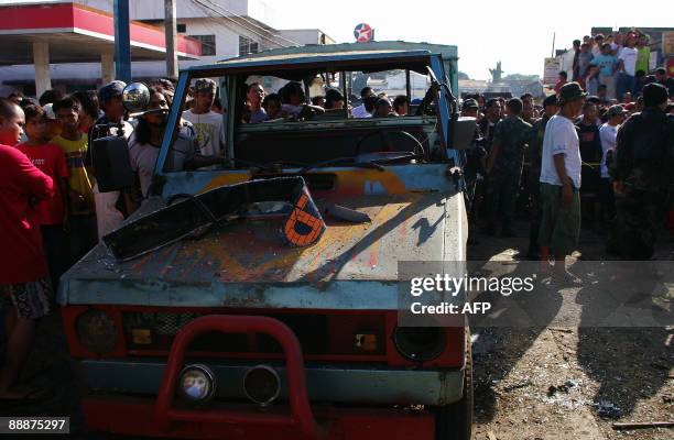 Large crowd gather next to a destroyed vehicle after a bomb explosion at a commercial centre in Jolo, on the island of Mindanao on July 7, 2009. At...