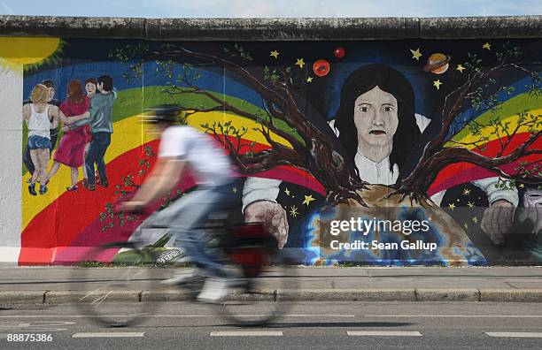 Bicyclist passes by a restored mural by artist Catrin Resch at a surviving portion of the former Berlin Wall known as the East Side Gallery on July...