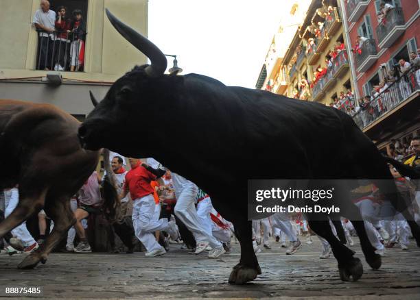 Fighting bulls and runners take a corner at Estafeta street during the 1st day of the San Fermin running of the bulls fiesta on July 07, 2009 in...