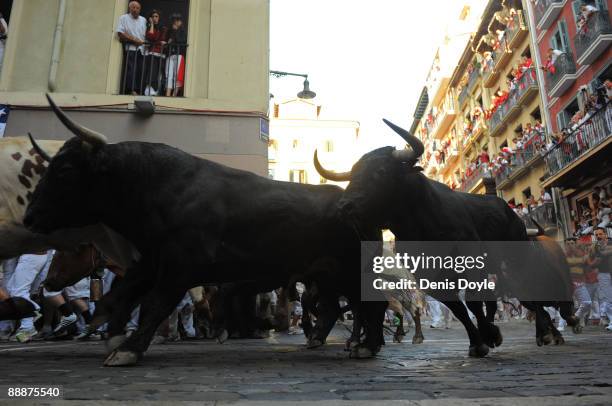 Runners lead fighting bulls around a corner at Estafeta street during the 1st day of the San Fermin running of the bulls fiesta on July 07, 2009 in...