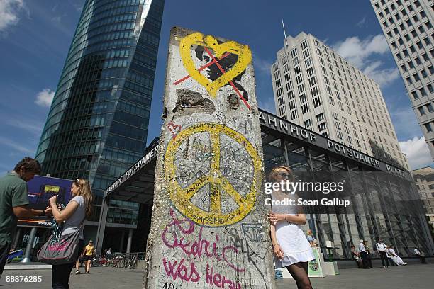 Tourist poses for a snapshot at a surviving piece of the former Berlin Wall at Potsdamer Platz on July 7, 2009 in Berlin, Germany. The Berlin Wall...