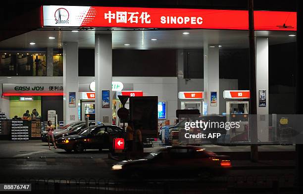 To go with AFP story by Joelle Garrus: FINANCE-ECONOMY-CHINA-OIL-ACQUISITIONS A woman waits beside a taxi fuelling up at a Sinopec gas station on...