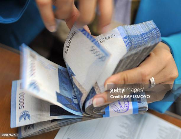 Money changer counts a wad of Indonesian Rupiah at her shop in Jakarta on July 6, 2009. Japan is to agree to provide some 15.6 billion dollars in...