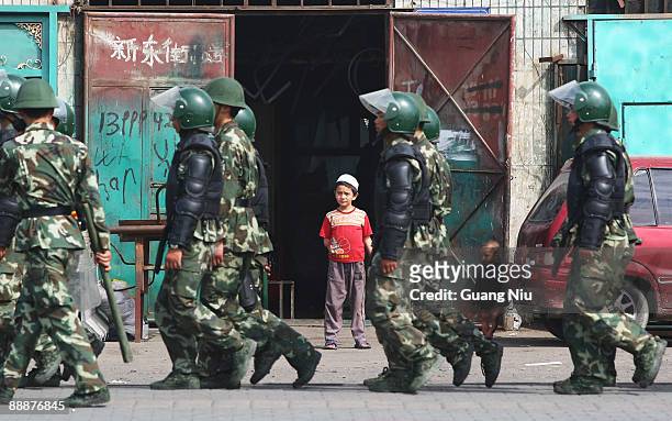 Uighur children watch policemen pass their home as they head to face protestors on July 7, 2009 in Urumqi, the capital of Xinjiang Uighur autonomous...