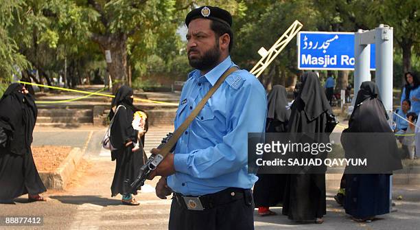 Police-man stands alert as Pakistani women arrive at a security checkpoint outside the Red Mosque in Islamabad on July 7, 2009. More than 1,000...