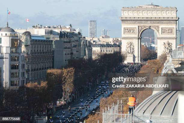 Motorcyclists ride during a 'popular homage' to late French singer Johnny Hallyday on the Champs-Elysees avenue on December 9, 2017 in Paris with the...