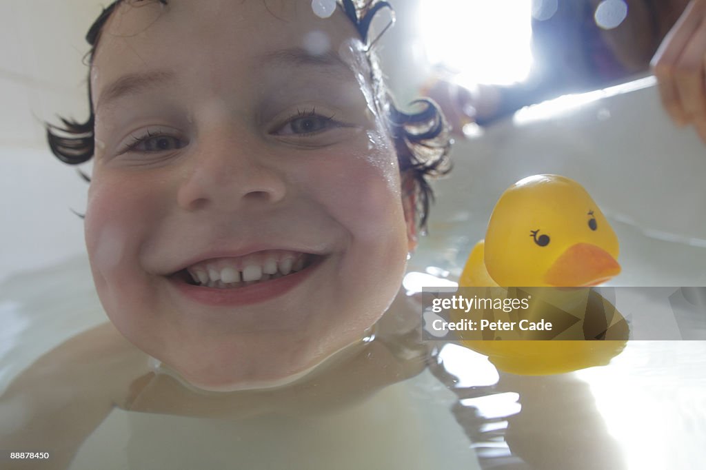 Boy in bath with rubber duck