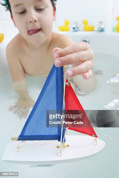 boy in bath playing with boat - boat in bath tub foto e immagini stock