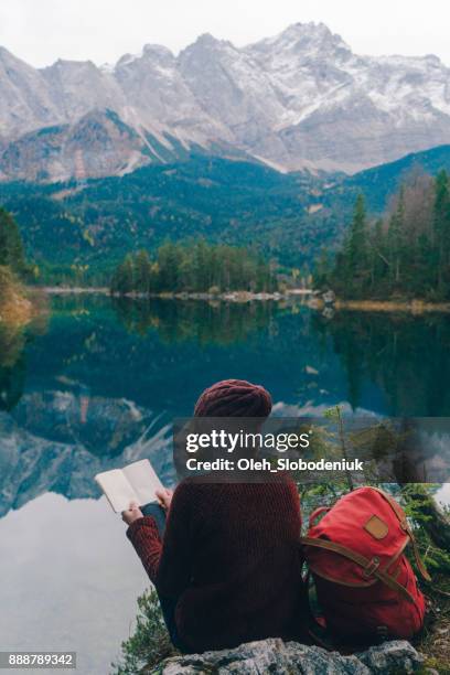 woman reading on the background of  scenic view of eibsee lake in alps - travel with book stock pictures, royalty-free photos & images