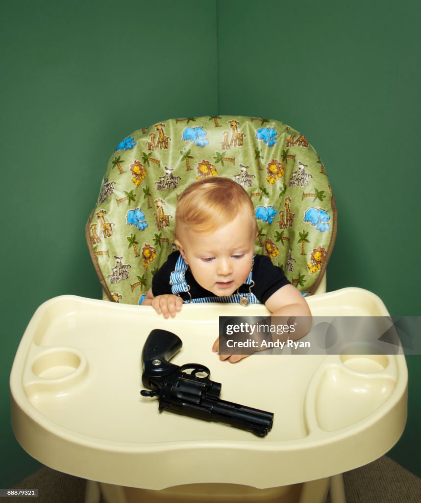 Child in High Chair with Revolver