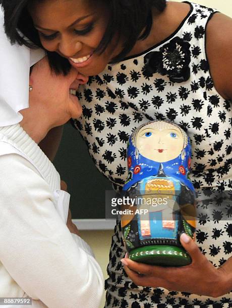 First Lady Michelle Obama hugs an elderly nurse while holding a traditional Russian matreshka nesting doll during a visit to the Sisters of Mercy St....