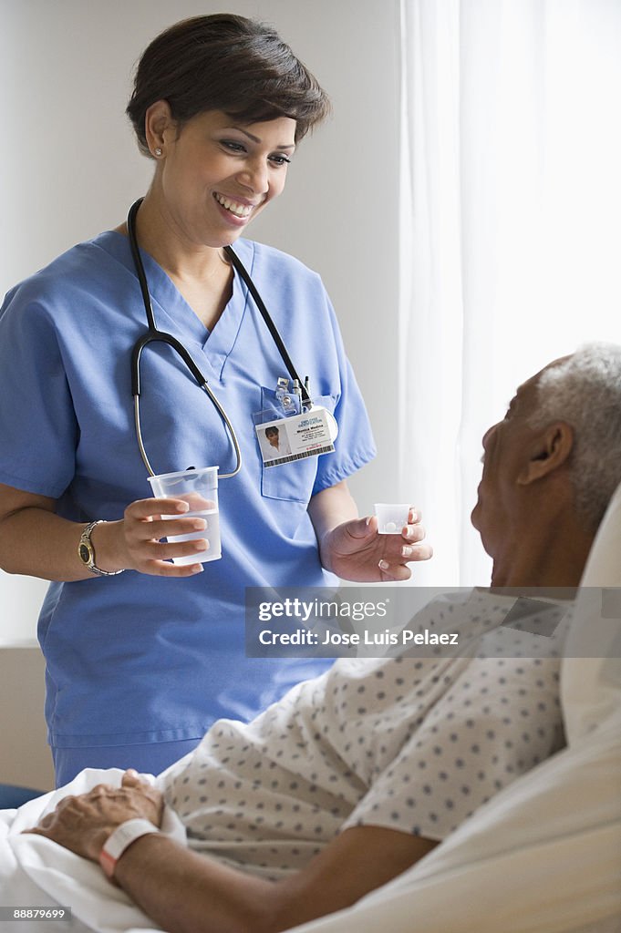 Nurse giving elderly male patient medication