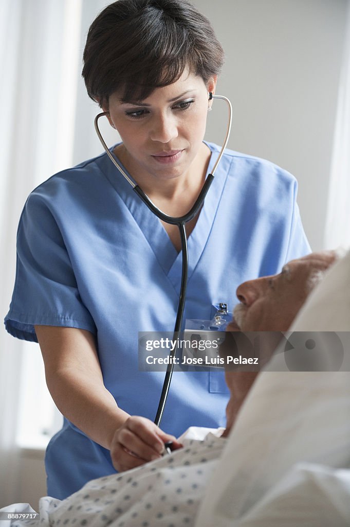 Nurse checking elderly male patient with stethosco