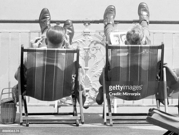 Holiday scenes at Brighton Two holidaymakers put their feet up on Brighton promenade and enjoy the sunny weather, 7th July 1963.