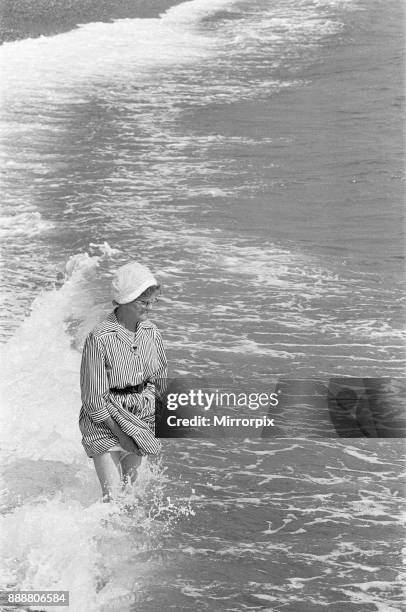 Holiday scenes at Brighton Elderly woman paddling in the sea holding her skirt up so it does get wet, 7th July 1963.