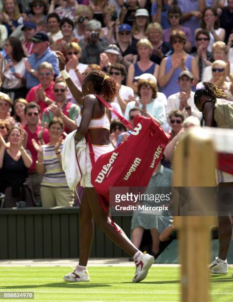 Venus and Serena Williams at the end of their Wimbledon July 2000 semi final match walking off court .