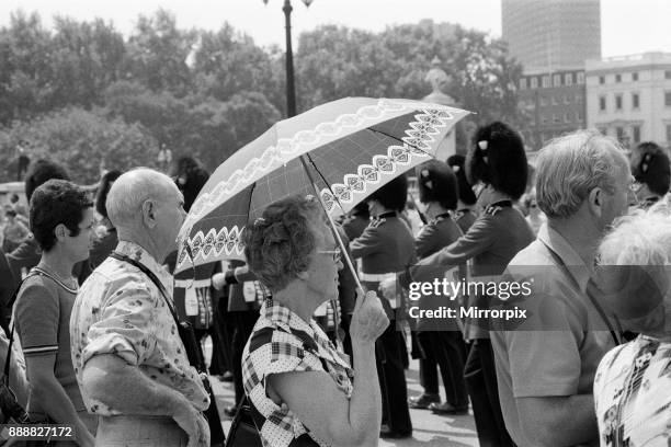 Changing of the Guard in London today. An umbrella serves as a sun-shade for a spectator, 8th June 1976.