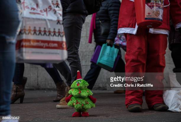 Shoppers walk past a toy Christmas tree and carol singers on Carnaby Street on December 9, 2017 in London, England. With two weeks of shopping time...