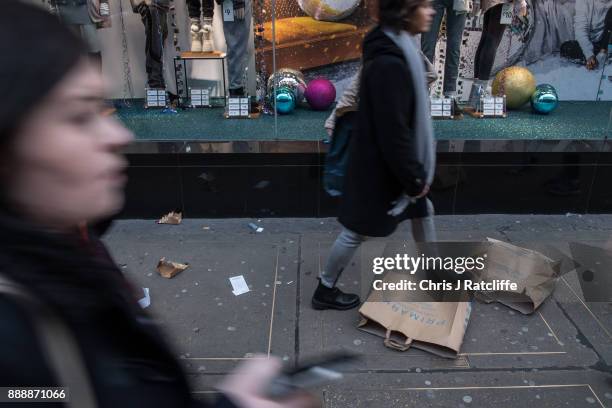 Woman walks over Primark shopping bags that litter the pavement outside the Primark flagship store on Oxford Street on December 9, 2017 in London,...