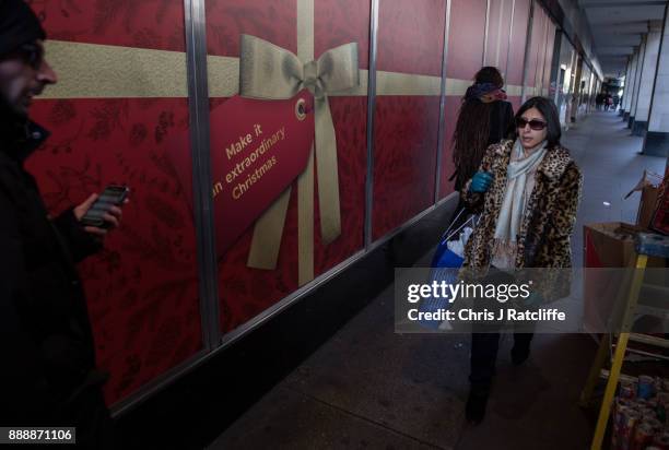 Shoppers walk past an advertising board on Oxford Street on December 9, 2017 in London, England. With two weeks of shopping time left before...