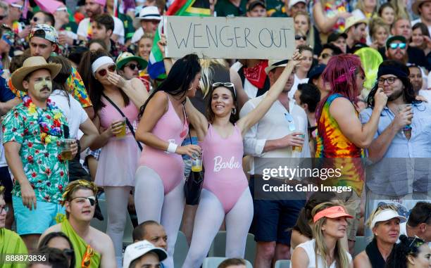 Spectators in fancy dress holding a 'Wenger Out' sign cheer during day 1 of the 2017 HSBC Cape Town Sevens at Cape Town Stadium on December 09, 2017...