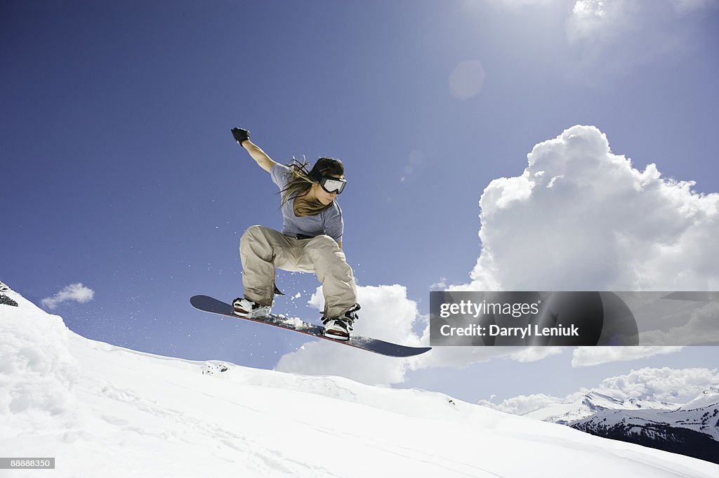 Female snowboarder jumping through air