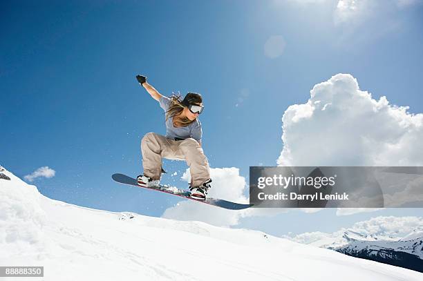 female snowboarder jumping through air - woman snowboarding stock pictures, royalty-free photos & images