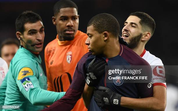 Paris Saint-Germain's French forward Kylian MBappe , held by Lille's French forward Yassine Benzia reacts next to French assistant referee Yannick...