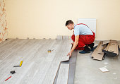 handyman laying down laminate flooring boards