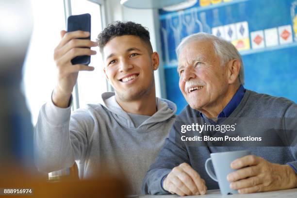 grandfather and late teens grandson taking a selfie - grandfather and grandson stock pictures, royalty-free photos & images