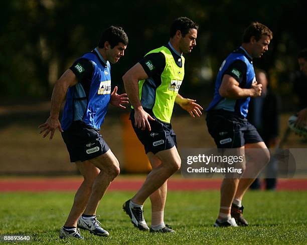 Michael Ennis, Brett White and Josh Perry warm up during a New South Wales Blues training session at the Regional Athletics Centre on July 8, 2009 in...