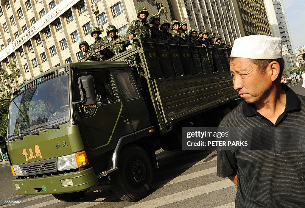 An Ethnic Uygur man watches as an army t