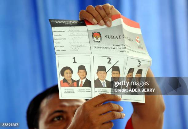 An Indonesian official holds up a checked presidential election ballot paper during a counting at a polling station in Bogor on July 8, 2009....