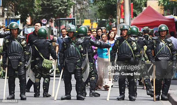 Some Uighur people walk near police as they form a line across a street on July 8, 2009 in Urumqi, the capital of Xinjiang Uighur autonomous region,...