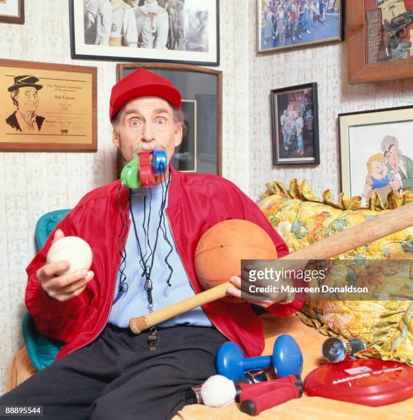 Twenty years on, American comic actor Sid Caesar recreates his role as Coach Calhoun in the 1978 musical film 'Grease'. On the wall behind him is a...